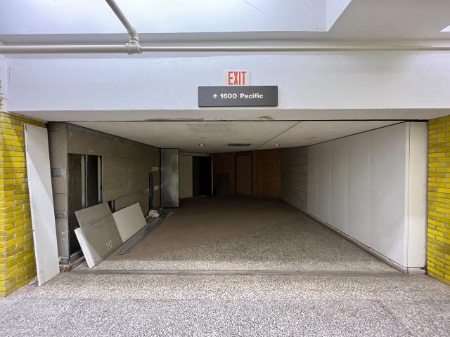 An emergency exit and street sign reading 1600 Pacific point to a boarded up wall